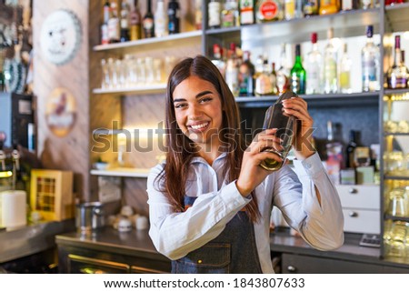 Young female worker at bartender desk in restaurant bar preparing coctail with shaker. beautiful young woman behind bar making coctail Royalty-Free Stock Photo #1843807633