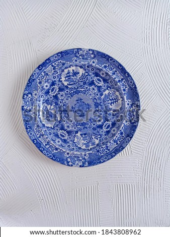 antique blue plate is over 45 years old with textured white background. taken from above Royalty-Free Stock Photo #1843808962