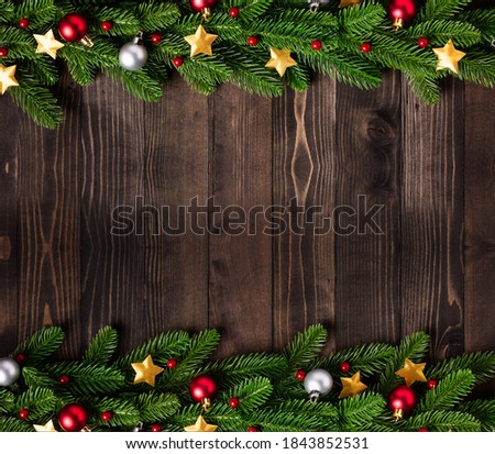 Christmas holiday garland border, Top view of tree fir branches, and Xmas stars ornament bauble decor on black wood background with copy space
