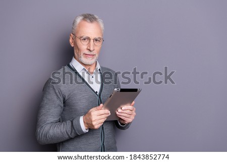 Portrait of his he nice attractive calm peaceful content business shark wearing casual formal-wear holding in hands e-book browsing e-commerce isolated over gray pastel background
