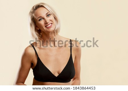 Smiling young blonde woman in black sports top. Yellow background. Activity and a healthy lifestyle. 