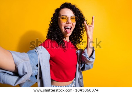 Photo of young girl take selfie tongue-out show horns wear red t-shirt jacket sunglass isolated yellow color background