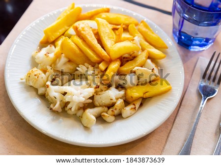 Picture of grilled tasty cuttlefish served with french fries at plate