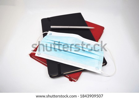 notebook pile with mask and pen. stay health at working time