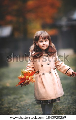 A little girl walks on the street in autumn