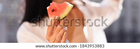 cropped view of brunette woman in beige underwear and white shirt eating watermelon on balcony, horizontal banner