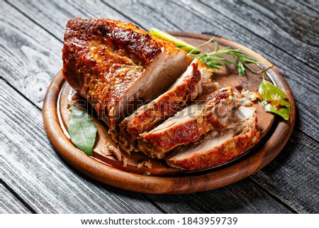 Sunday roasted pork tenderloin, juicy and succulent oven-baked piece of meat rubbed with mustard and spices: rosemary, bay leaf, lime juice, and pepper on a wooden background, close-up, top view Royalty-Free Stock Photo #1843959739