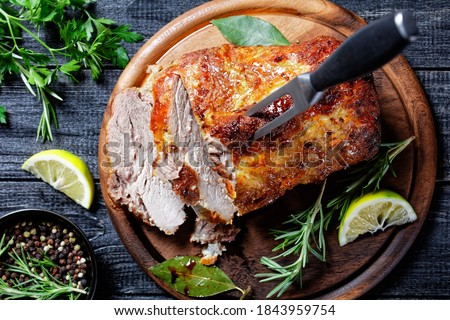 Sunday roasted pork tenderloin, juicy and succulent oven-baked piece of meat rubbed with mustard and spices: rosemary, bay leaf, lime juice, and pepper on a wooden background, close-up, top view Royalty-Free Stock Photo #1843959754