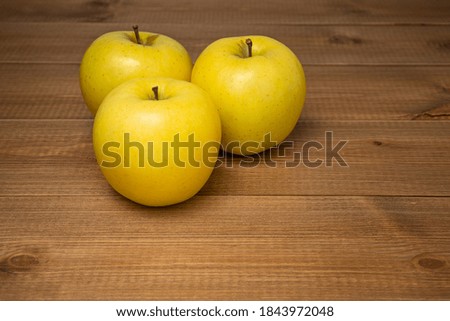 Three beautiful yellow ripe Golden apples on wooden table. Sweet and juicy fruits.