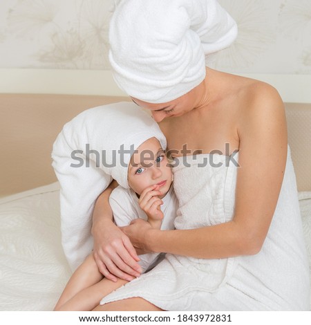 Mother and her daughter playing and hugging in the bed. Happy loving family. Beautiful young woman being kissed by a cute little girl. Happy mother's day.