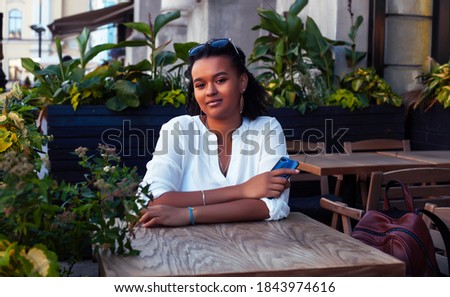 young pretty african girl posing cheerful in cafe outdoor, lifestyle people concept