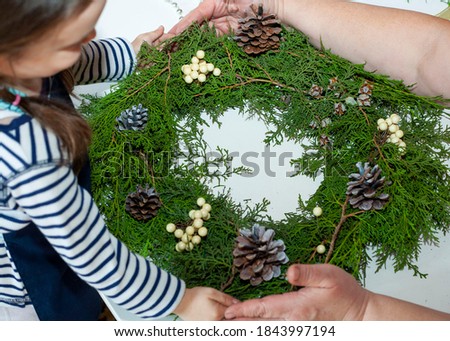 Granddaughter and grandmother make a Christmas wreath. Little girl helps to make a wreath. New Year's decorations. Christmas decorations.