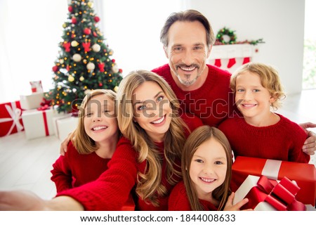 Photo of full big family five people meeting three little kids hold present box bow ribbon mom make shoot selfie wear red jumper in living room x-mas tree lights many gifts indoors