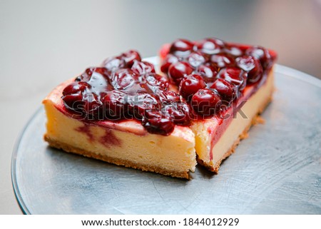 Two slices of cherry cheese cake divided into portions on a metal plate Royalty-Free Stock Photo #1844012929