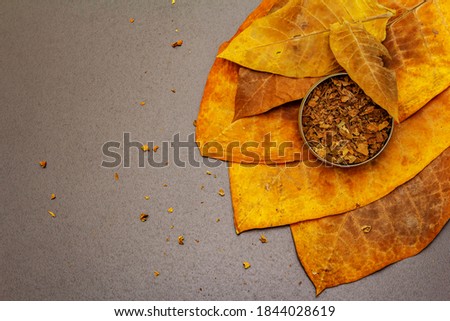 Shredded tobacco in a tin box. High quality cured big leaves to make cigars. Black stone concrete background, top view Royalty-Free Stock Photo #1844028619