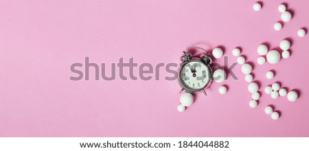 New Year midnight clock and white glitter ball decorations on pink background with copy space 