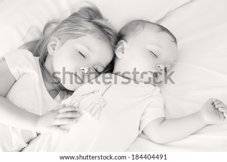 charming little brother and sister asleep embracing on white background ( black and a white )