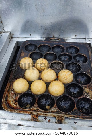 Street Food. Takoyaki in molds sold in a traveling cart. Selective focus. 