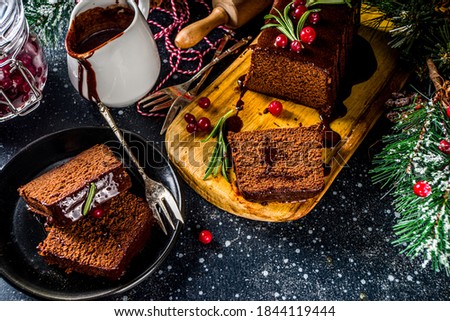 Chocolate Gingerbread Cake on festive background. Traditional Gingerbread cake with dark chocolate topping, cranberry and rosemary, on Christmas decorated table, copy space