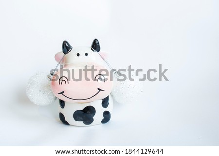 Figure in the shape of a cow in black and white decorated with Christmas decorations on a white background. New year of the bull
