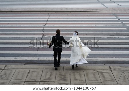 Conceptual symbolic photography. At the crosswalk, the bride in white, the groom in black. Metaphor of the beginning, the transition from one state to another, black and white stripes a person's life