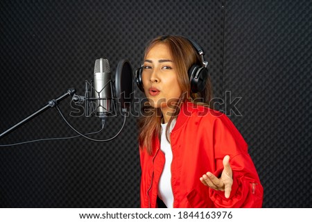 young attractive Asian woman musician singer in recoding studio with microphone. Performance arts concept.