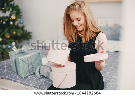 In a beautiful decorated room with a Christmas tree is sitting a young girl with presents
