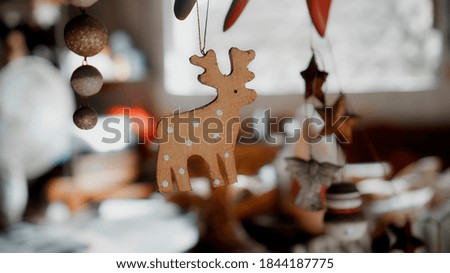Little wooden Christmas toys deer hanging on a thread in the house