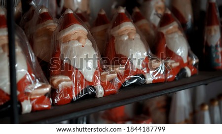 Small Christmas wooden toys of santa claus sits in the house in plastic packaging