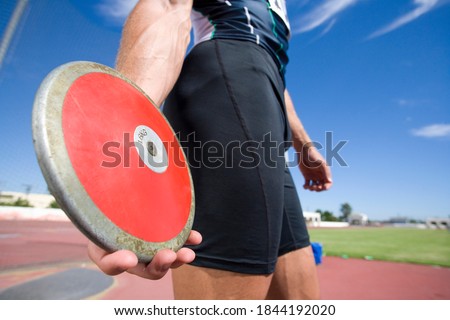 The midsection of a male athlete preparing to throw the disk in discus throw competition.