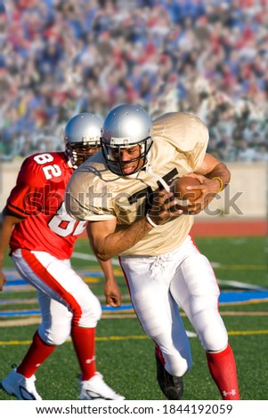 Determined football player running with the ball at opposing players during a competitive game.