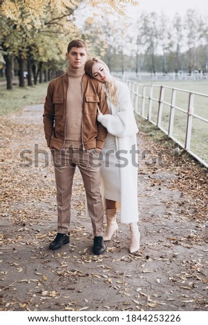 Beautiful young couple in autumn walks with dogs, pomeranian, in the park