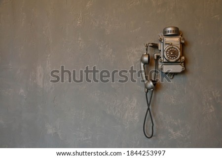Old vintage wired telephone for communication hangs on textured gray wall. Antique phone from past for background. History of telephone in world. Concept of communications and telegraph. Copy space Royalty-Free Stock Photo #1844253997