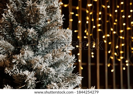 Close-up of Christmas or new year tree with decorative elements and artificial snow. Selective focus of Christmas tree in the living room interior. Concept of stylish christmas backgrounds. Copy space