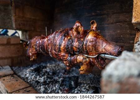 Serbian "Pecenje" pig on a skewer turning over hot ash for an Orthodox event called "slava" Royalty-Free Stock Photo #1844267587