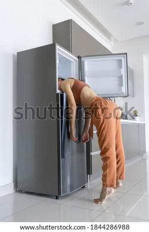 On a hot day, the girl cools with his head in the refrigerator. Broken air conditioner. Royalty-Free Stock Photo #1844286988