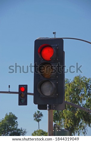 Close-up low angle view of a traffic signal showing a red light and a second red light in the background