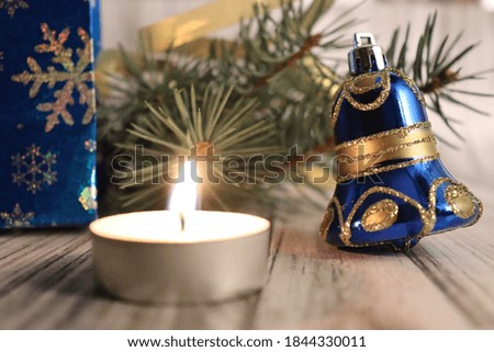 decoration for Christmas tree bells, gift, spruce branch and a burning candle