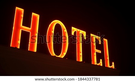 Hotel, red neon sign on the building illuminated at night. High quality photo
