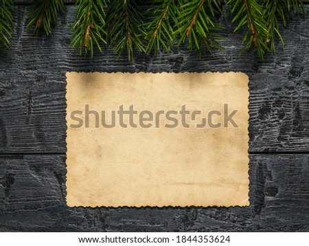 A sheet of old worn paper on a wooden background with fir branches. Form for wishes and greetings. A letter requesting a gift.