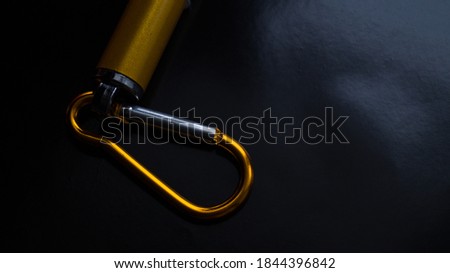 Bottom of a laser pointer with multiple modes on a dark background. Metal carbine on the laser. Point to something. Children's toy. Small yellow metal flashlight. Place for text.