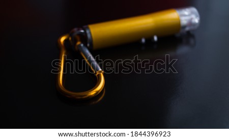 Laser pointer with multiple modes on a dark background. Metal carbine on the laser. Point to something. Children's toy. Small yellow metal flashlight. Place for text. Focus on the carbine. Royalty-Free Stock Photo #1844396923