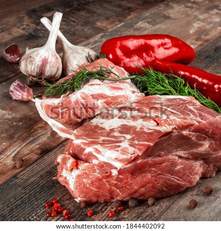 Piece of raw meat ready for preparation with greens and spices. rustic wooden background. close-up. square picture