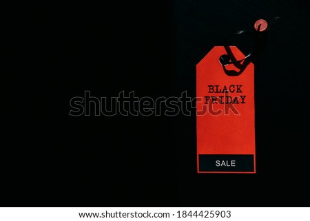 Black friday shopping sale concept. Text on red tag on black wooden background. Copy space.