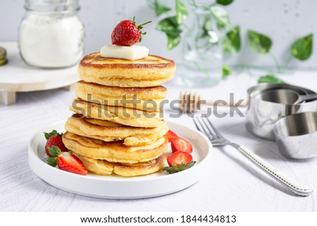 Close up view of a stack of pancakes with butter, strawberry and honey, bright mood, selective focus Royalty-Free Stock Photo #1844434813