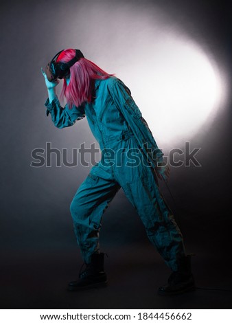 Virtual reality and futurism. Cyberpunk concept, a gamer with pink hair. Young woman in overalls and virtual reality glasses, is in a simulation, black background