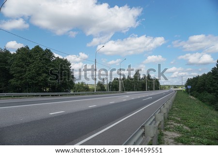 Asphalt road among forests and fields. A beautiful journey by car. Nature stock photo background