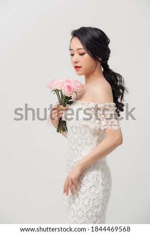 Young beautiful pretty Asian girl standing and holding pink roses over white background.