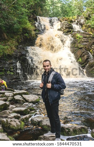 Happy man on the background of a beautiful waterfall, vertical