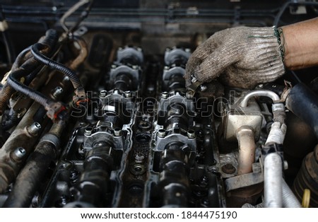 Opened old engine block interior part of car for repairing The mechanic wears soiled gloves on the damaged parts of the engine.Engine repair